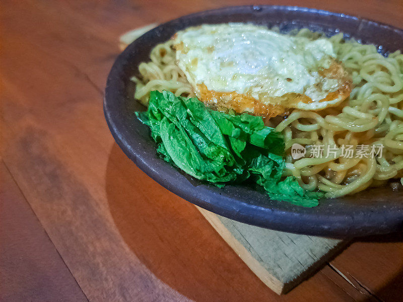 美味的Mie Goreng Telur Cobek Bakar或烤臼煎蛋卷，鸡蛋炒面与绿芥末。食品菜单。